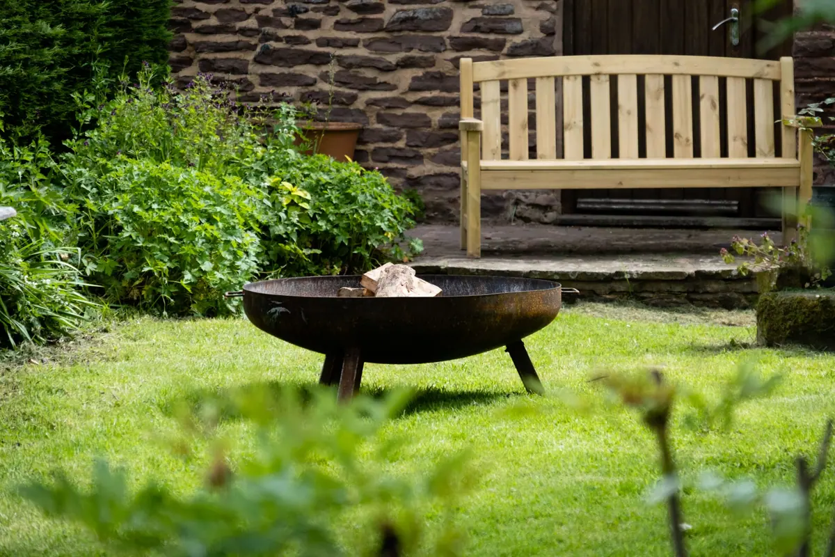 The firepit on the lawn with a bench behind it