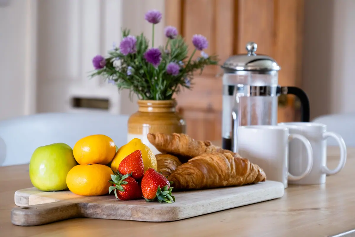 Croissants, strawberries and coffee laid out on a board