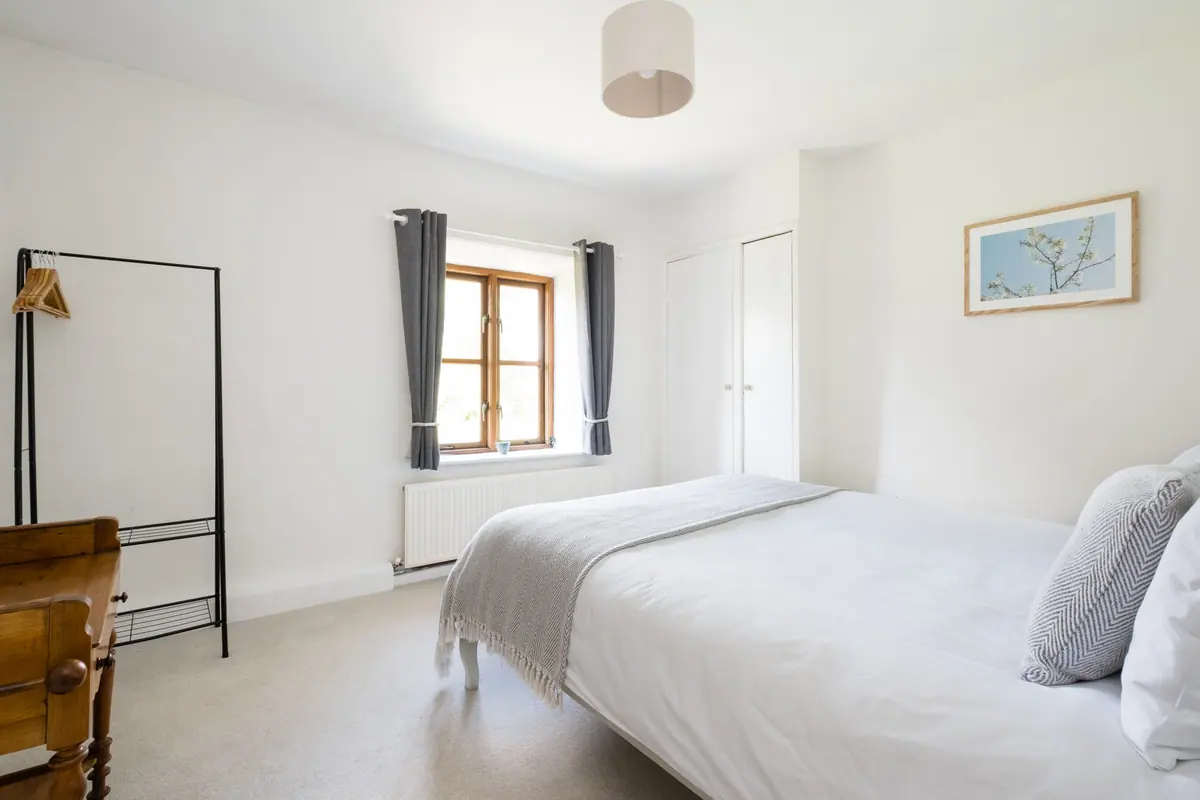 A king bed beside a window onto the fields
