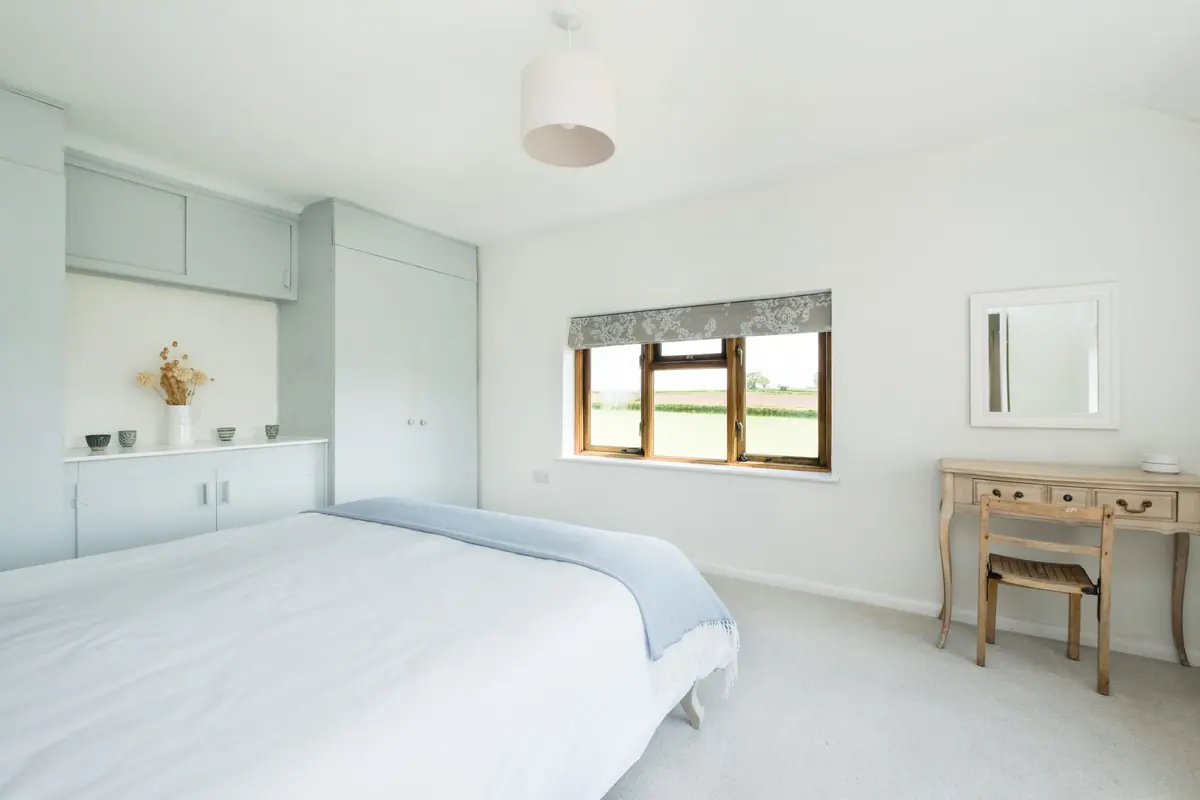A bedroom with fitted cupboards and a garden view